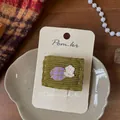 Detail van groene gebreide haarclip met geruite knoop op een vintage houten standaard - Groene Ruit Applicatie