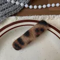 Dettaglio del fermaglio per capelli leopardato con trama soffice su un piatto bianco - Fermaglio Leopardato