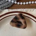 Dettaglio di un fermaglio per capelli in peluche leopardato su un piatto di porcellana - Molletta Triangolo Leopardato