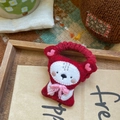 Détail d'un chouchou en feutre rouge avec broderie mignonne et nœud rose sur plateau - Ours avec nœud