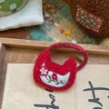 Gros plan d'un chouchou en feutre rouge fait main avec des broderies de fleurs fines - Embroidered Floral Cat