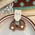 Detailansicht von zwei braunen Häkelblumen-Haargummis mit weißen Pompon-Mitten - Kaffeebraune Blumen Haargummis