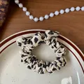 Dettaglio dello scrunchie leopardato con orecchie di coniglio su piatto decorativo - Scrunchie con Fiocco / Beige