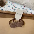 Detail of elastic brown bear hair tie with orange hand-stitched leather on floral backdrop - Brown Bear Hair Tie