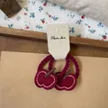 Détail de chouchous pomme rouge en feutre avec élastiques ondulés sur fond de texture vintage - Chouchou Pomme Rouge