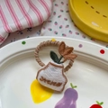 Gros plan d'un élastique spirale marron avec broderie détaillée de vase et de fleur - Petit Pot de Fleurs