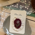 Detailed macro view of handmade embroidered floral fabric brooch with lace trim on paper card - Embroidered Floral Style / Red Floral Lace Hair Clip