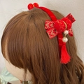 Detail van rode fluwelen haarband met gouden strik, witte parels en rode kwastjes - Rood Strik Haarband
