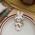Gros plan d'un chouchou lapin en tissu blanc fait main avec broderie carotte sur une assiette - Lapin à Écharpe Beige (NK1705)