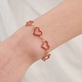 Detail van een elegante gouden armband met rode kristallen hartjes om een vrouwenpols - Hart Serie Armband (BS-J5479G)