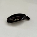 Macro shot of dark glossy banana clip with Barrette LaFrance gold lettering detail - Large / Red Brown