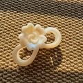 Dettaglio della clip per capelli a fiore in resina beige perlata su tessuto testurizzato - Forma Infinito / Beige