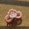 Detail view of pearlescent pink floral hair claw clip made of resin on a textured surface - Infinity Shape / Purple Pink