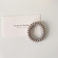 Minimalist morandi khaki spiral telephone wire hair tie on a designer card prop - Light Gray