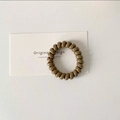 Spiral telephone cord hair tie in dark khaki resin on a minimalist white background - Chocolate