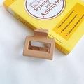 Detail shot of a rectangular matte claw clip in milk tea color on a book background - Light Coffee