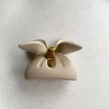 Detailed top view of matte beige bow-shaped hair claw clip with golden metal spring - Small Bowknot Style / Off White