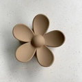 Macro shot of matte flower hair claw in light brown on a textured stone surface - Flower Style / Khaki