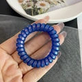 Nahaufnahme der matten Spiralhaargummis in Kleinblau mit irisierendem Perlmuttglanz - Transparent Iridescent Blue
