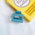 Matte teal rectangular hair claw clip with morandi finish on a yellow dictionary - Light Blue