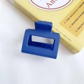 Matte Klein blue rectangular cutout hair claw clip on a yellow book background - Dark Blue