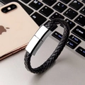 Detalle de la pulsera de cable USB de cuero trenzado negro junto a un portátil y móvil - Interfaz Micro-USB (20cm) / Negro