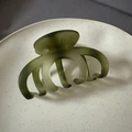 Macro view of olive green matte shark hair clip on a minimalist ceramic tray - Matte Green