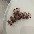 Détail macro de la grande pince à cheveux marron transparente de 13 cm avec ressort - Série Café Épissage