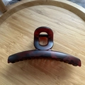 Détail d'une grande pince à cheveux mate rouge foncé sur un plateau en bois épuré - Écaille de Tortue Café Rouge Mat