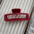 Detalle de pinza de pelo rectangular rojo oscuro en bandeja de terciopelo beige - Burdeos