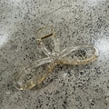 Detail shot of a large bow hair claw clip with gold foil flakes inside clear resin - Champagne