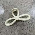 Detail view of the beige bow-shaped hair claw with strong interlocking teeth for firm grip - Glossy White