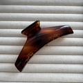 Detailed view of large glossy amber tortoiseshell hair claw clip on texture background - Tortoiseshell
