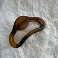 Dettaglio della pinza per capelli color ambra opaco con design a onde in resina - Caffè Giallo Opaco