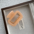 Vista detallada de una pinza para el pelo geométrica naranja en una caja de madera rústica - Naranja Claro Jelly