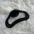 Dettaglio macro della molletta per capelli ondulata nero opaco con finitura liscia satinata - Nero Opaco