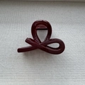 Detail view of glossy burgundy hair claw clip featuring a streamlined twist and metal spring - Bowtie Style Ankara Red / Medium