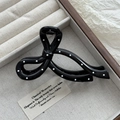 Detailed view of large black bow hair claw clip with white polka dots on jewelry box - Shiny Black Bowtie Style