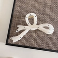 Detail of a creamy white bow hair claw clip with black polka dots and gold metal spring - Jelly White Fish Tail Style