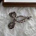 Dettaglio della pinza per capelli leopardata con molla dorata su sfondo di carta bianca - Leopardo Chiaro Stile Fiocco