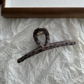 Dettaglio della molletta per capelli leopardata con molla dorata su carta strutturata - Leopardo Scuro Stile Lineare a Foro Singolo