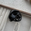Detail of a glossy black hollow triangle hair claw clip on a gray velvet jewelry tray - 3D Cross Twisted Style / Black