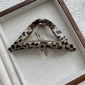 Macro di una grande clip per capelli a triangolo leopardata con molla in metallo dorato - Stile Triangolo