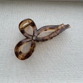 Vue détaillée d'une pince à cheveux en résine ambrée avec nœud sur fond de tissu gris - Style Nœud (Style B) / Écaille Ambre