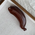 Deep brown jelly banana hair clip with shiny resin finish on a minimalist display tray - Dark Red