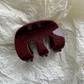 Detalle de una pinza para el pelo granate brillante con diseño de tres dientes sobre fondo blanco - Rojo
