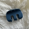 Primo piano di una pinza per capelli blu scuro lucido su sfondo di carta crema strutturata - Blu inchiostro