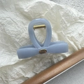 Detail view of light blue matte bow hair claw with gold spring and Hand Made metal tag - Straight Bow Metal Label