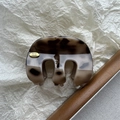 Détail de la pince à cheveux marbrée avec étiquette logo dorée Hand Made en métal - Écaille de Tortue Café Gris