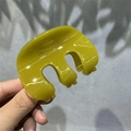 Close-up of olive green resin hair claw clip with glossy finish and three-tooth design - 8cm M-Shape / Yellow-Green